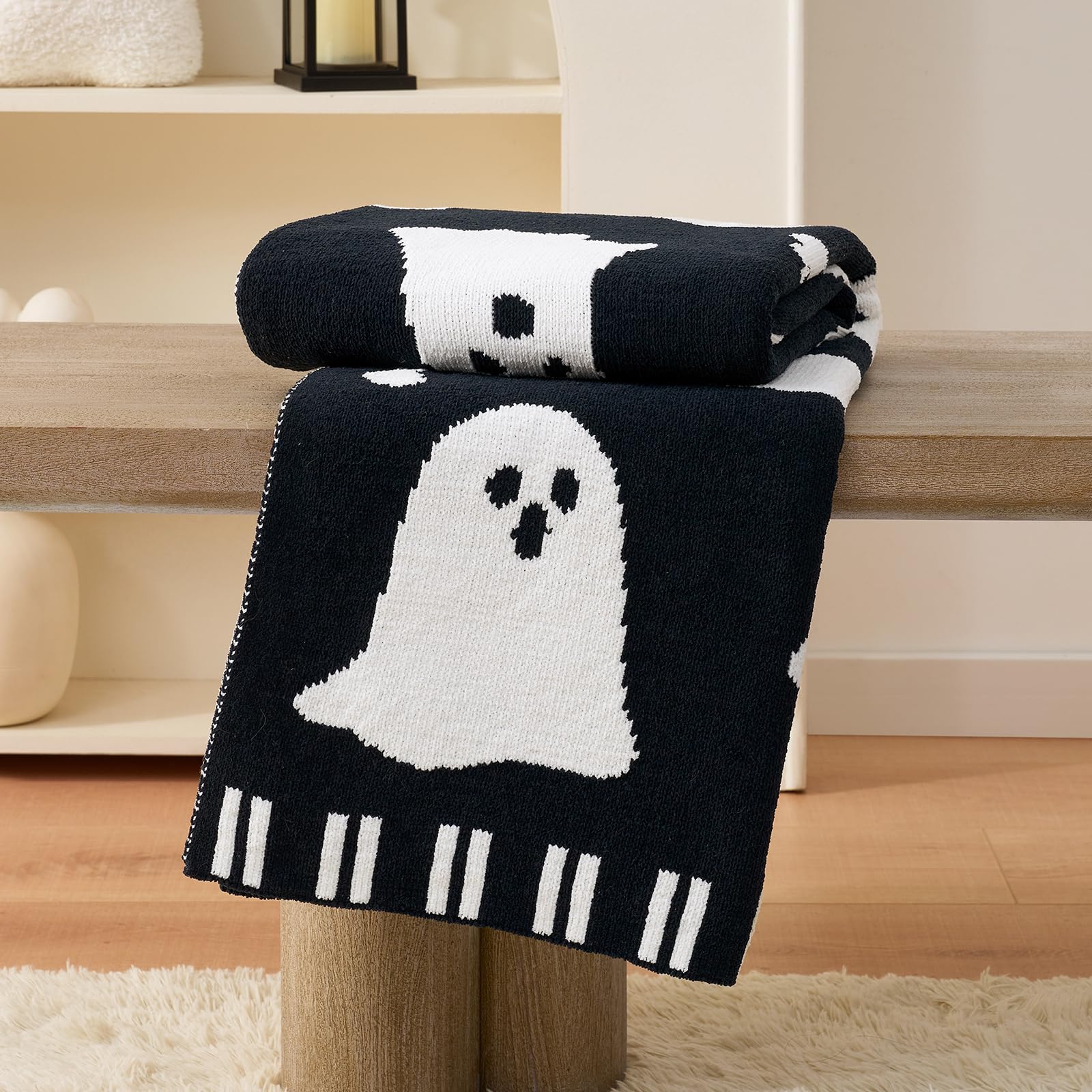 Black and white ghost-patterned blanket on a wooden table