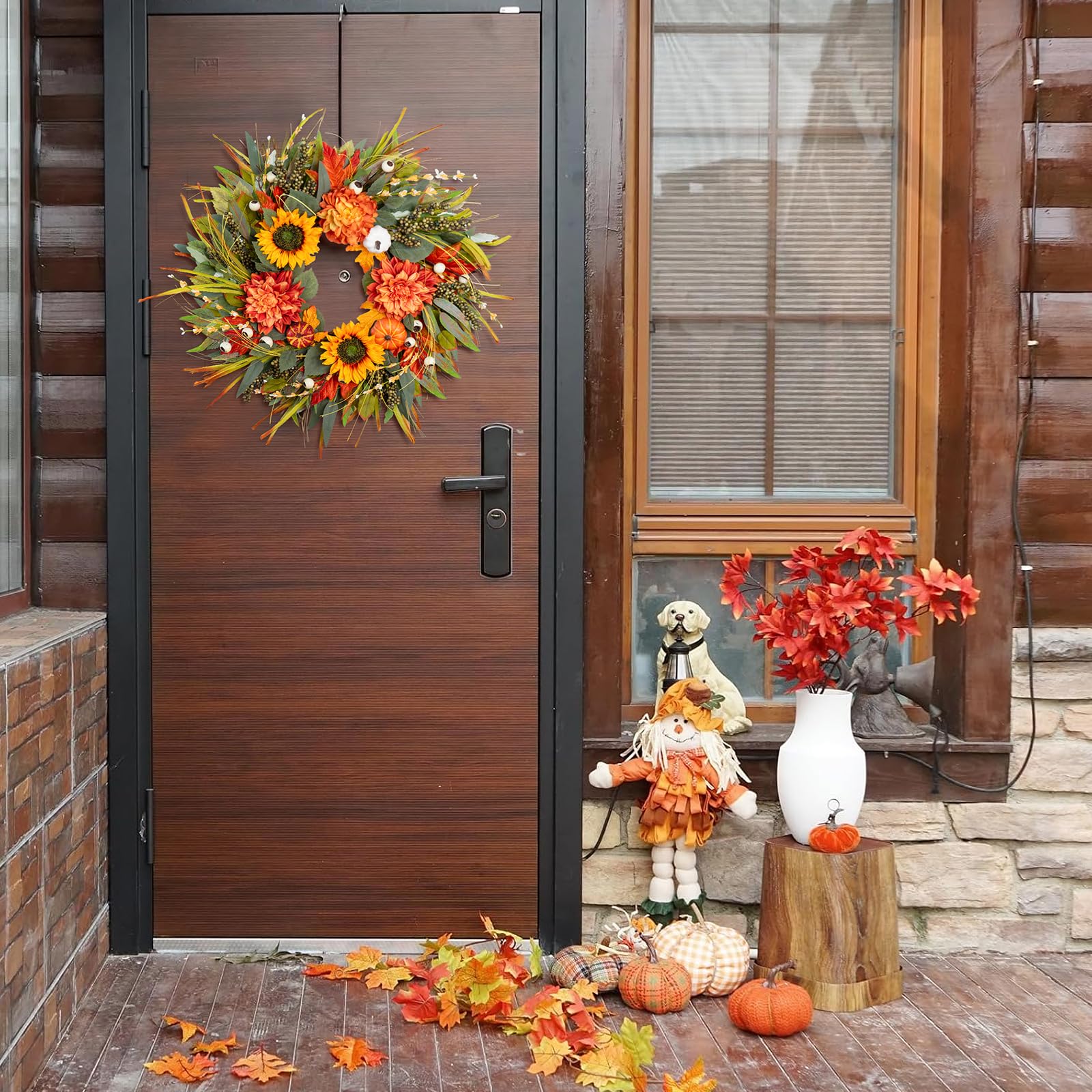 Decorative wreath on a wooden door with autumn-themed decorations outside.