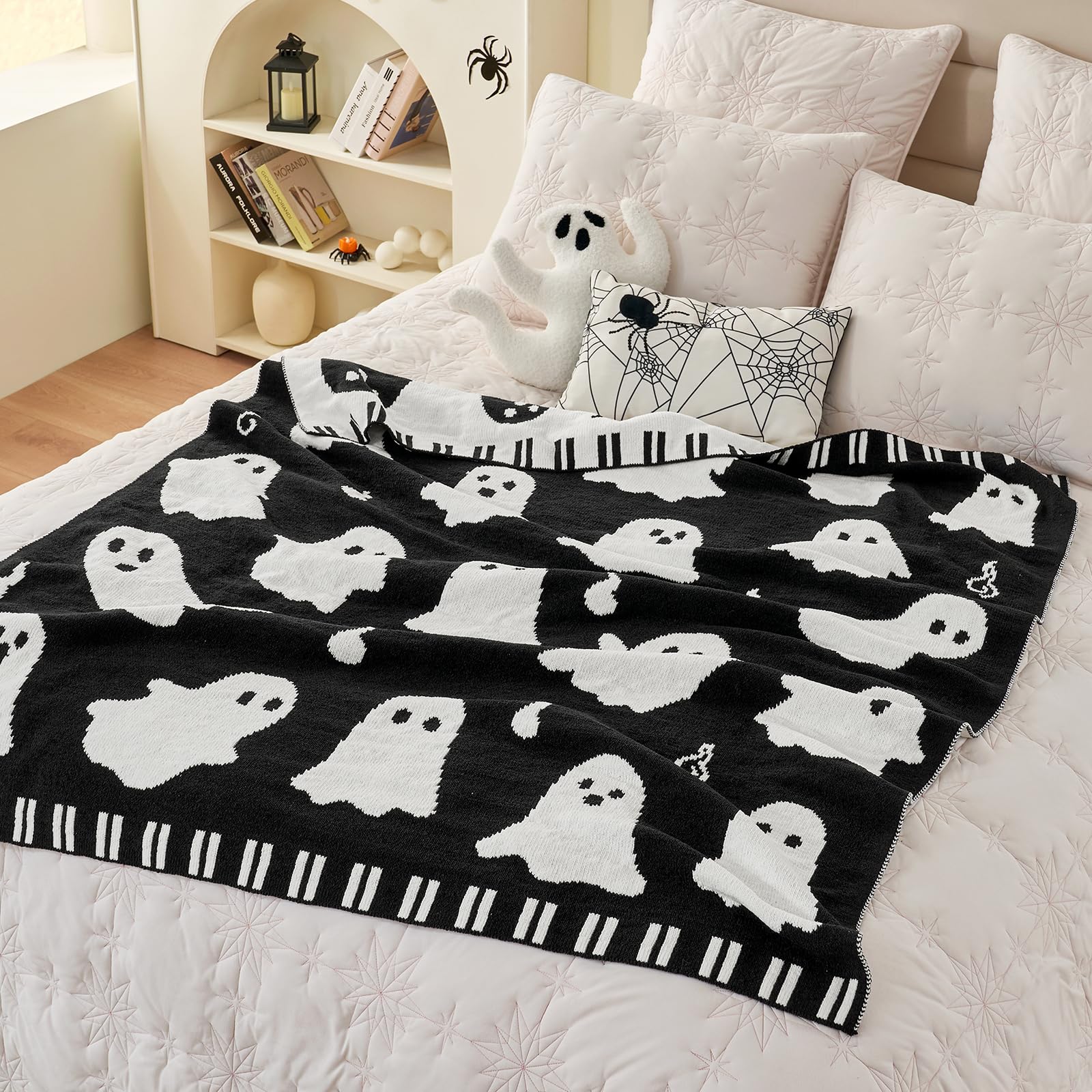 Black blanket with white ghost patterns on a bed