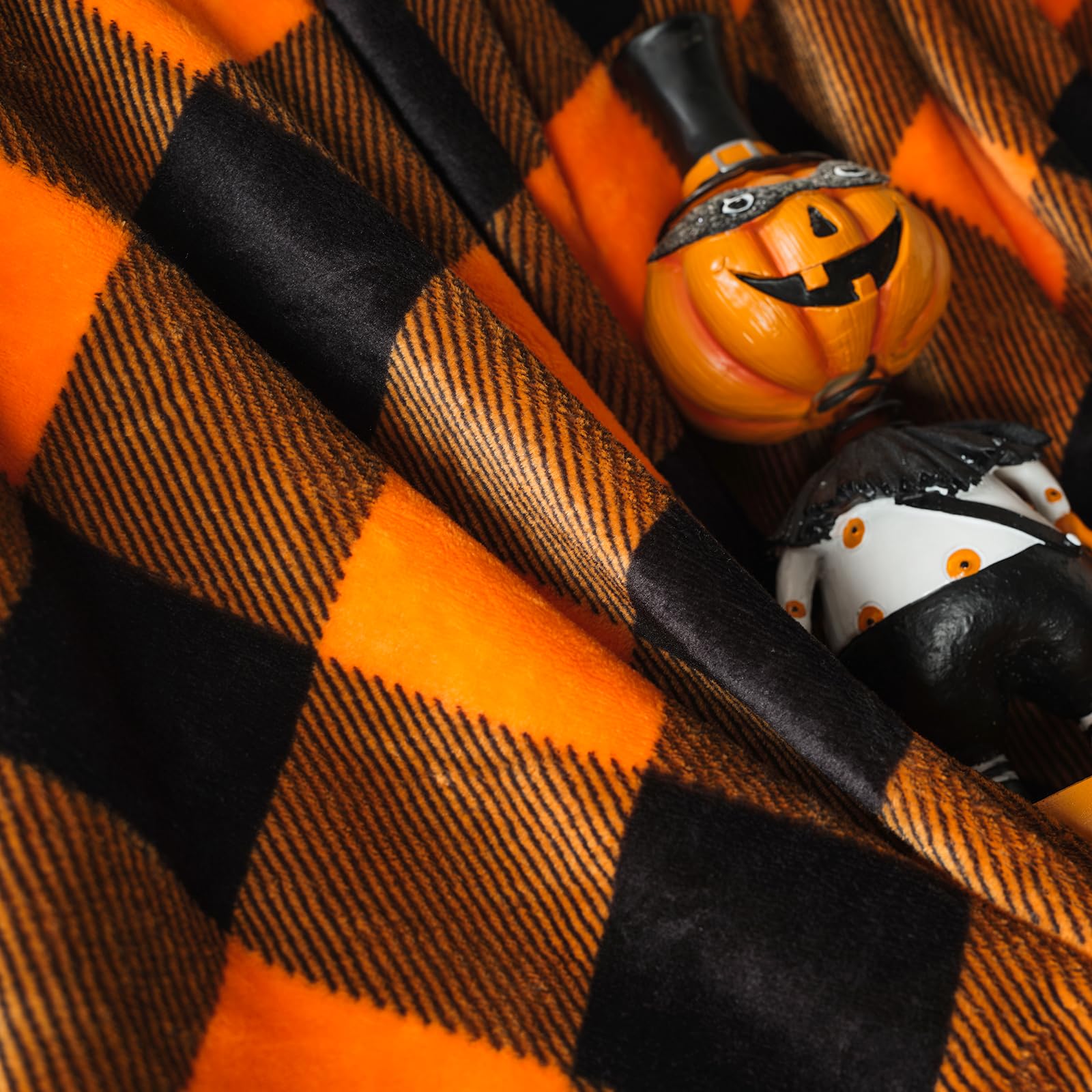 Halloween-themed decorations on black and orange plaid blanket fabric