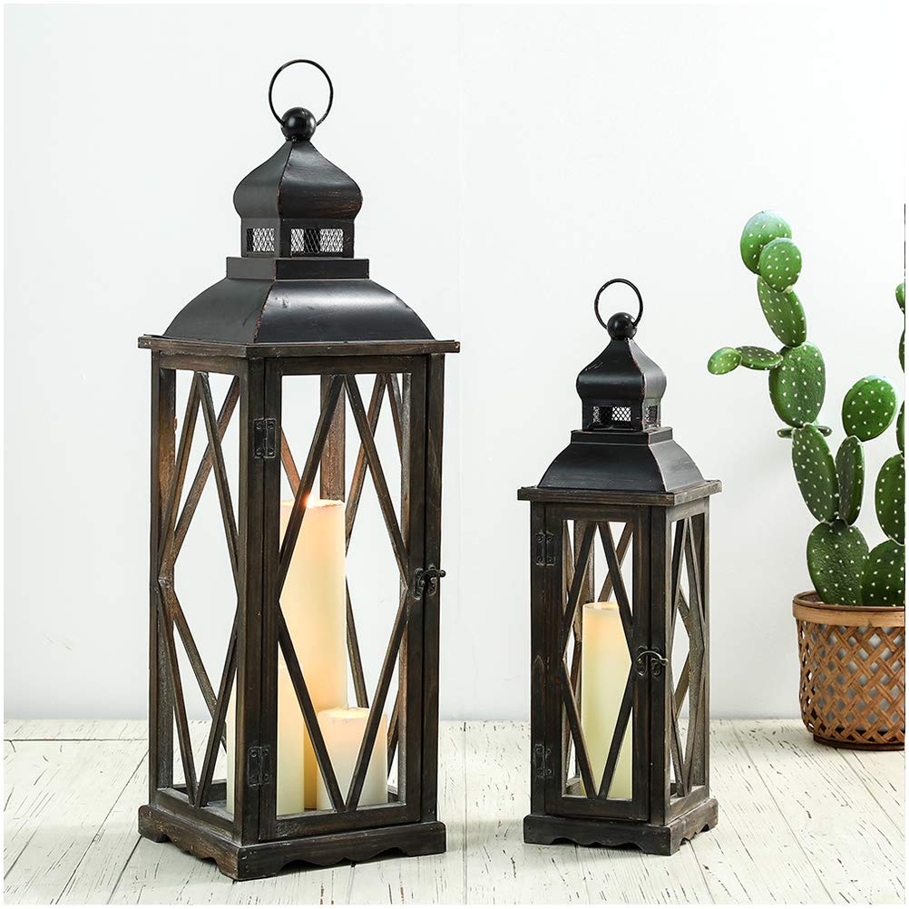 Two dark metal lanterns with candle lights on a light wooden floor, one larger than the other, with a cactus plant in the background.