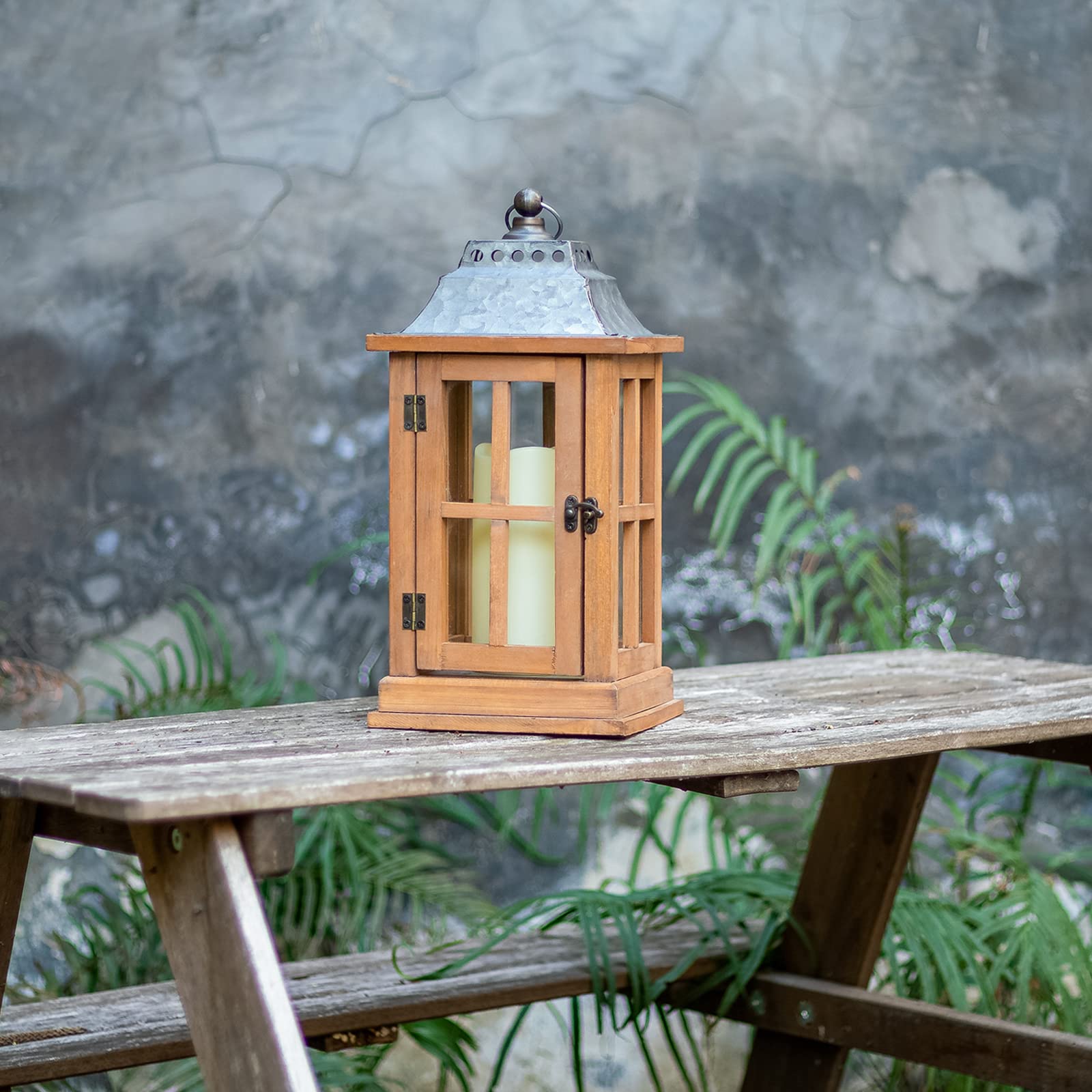 Wooden lantern with a candle on a wooden table outdoors.