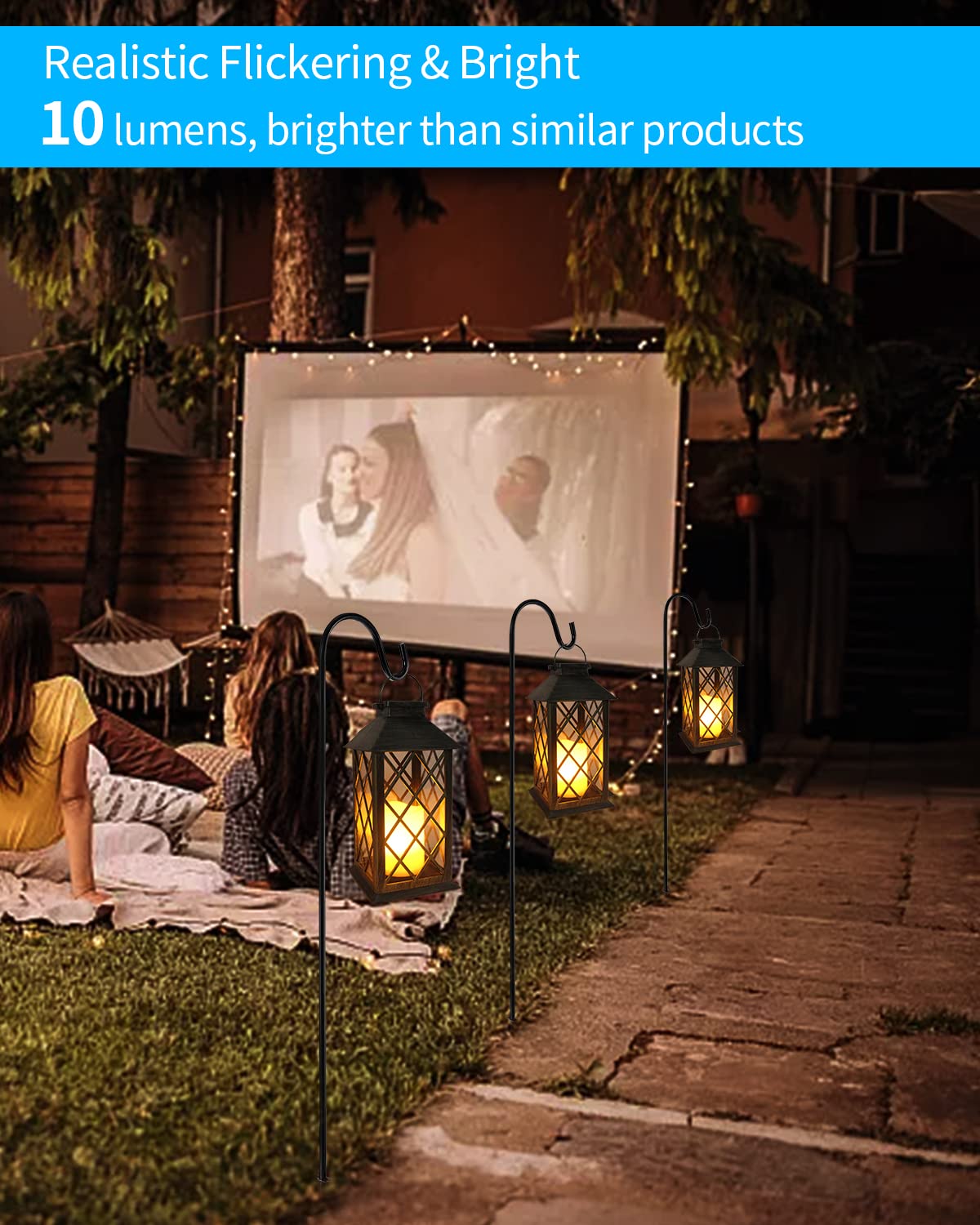 People watching a movie on an outdoor screen with lanterns around them.