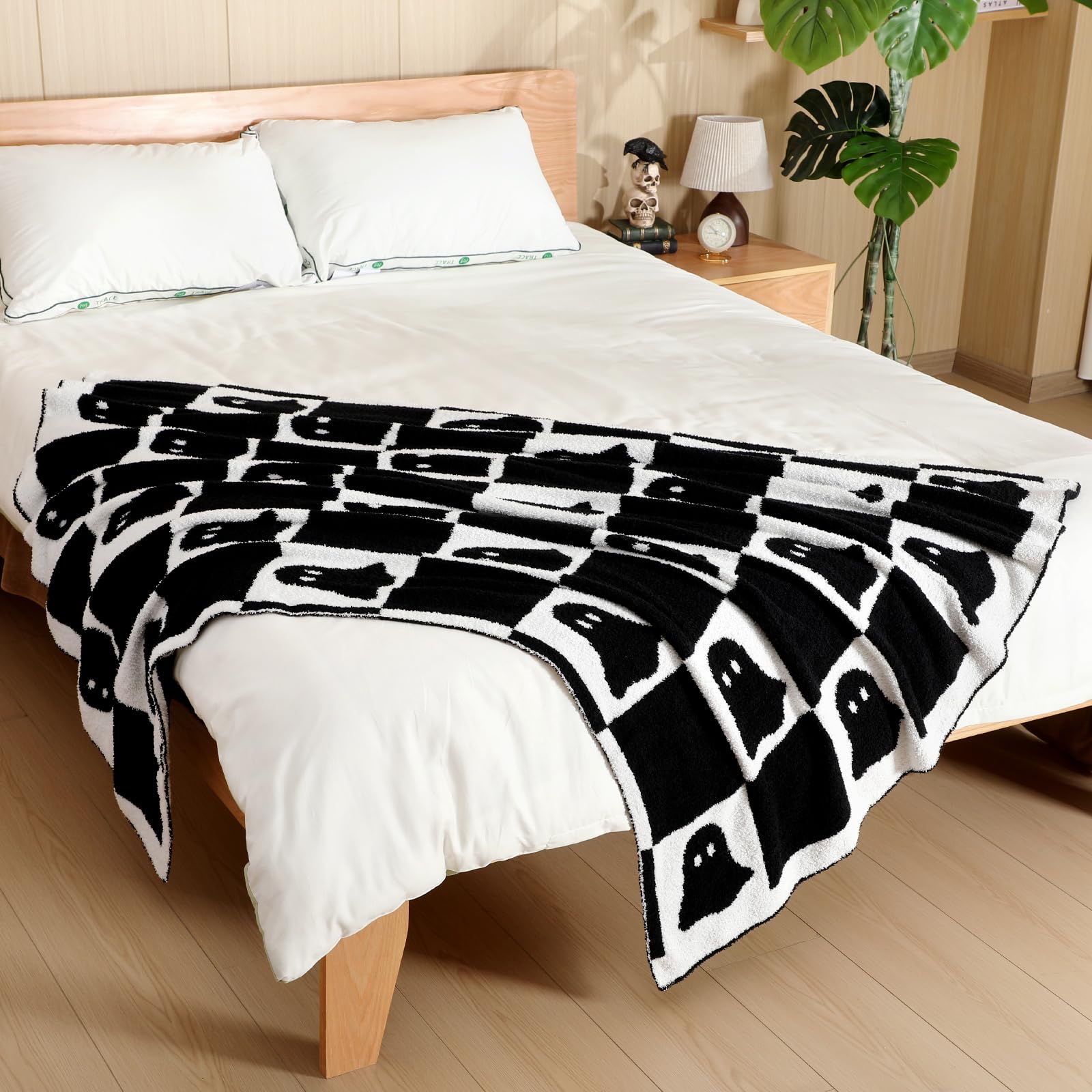 Black and white patterned Halloween ghost blanket draped over a bed in a bedroom setting.
