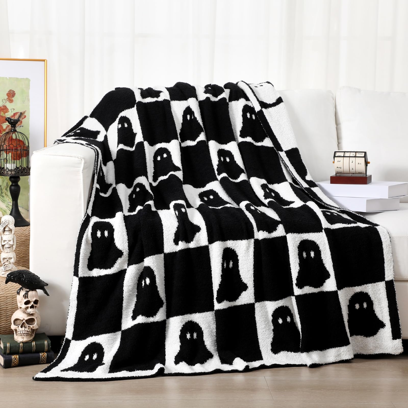 Black and white ghost patterned blanket draped over a couch in a living room.