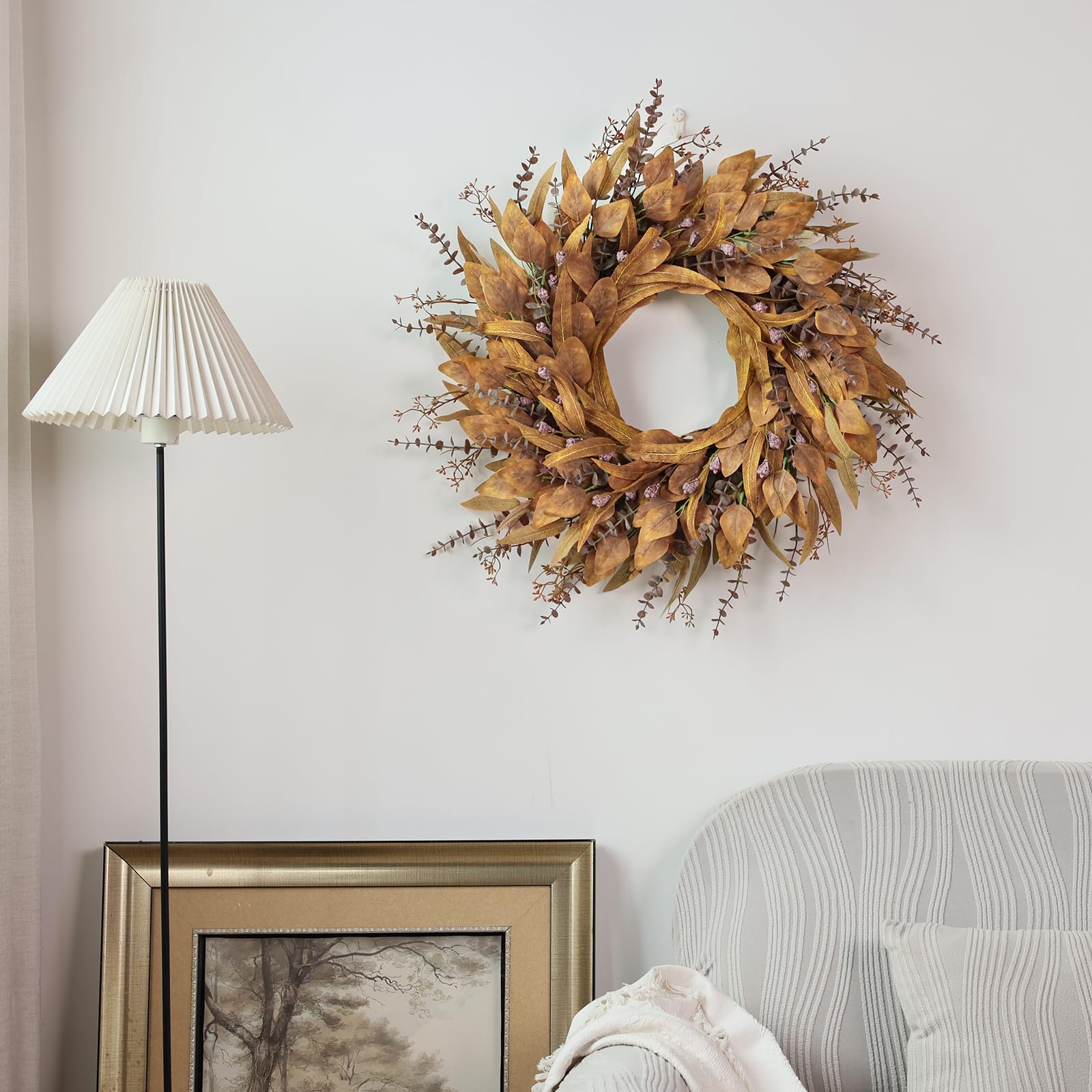 Decorative autumn wreath on a wall above a lamp and framed picture