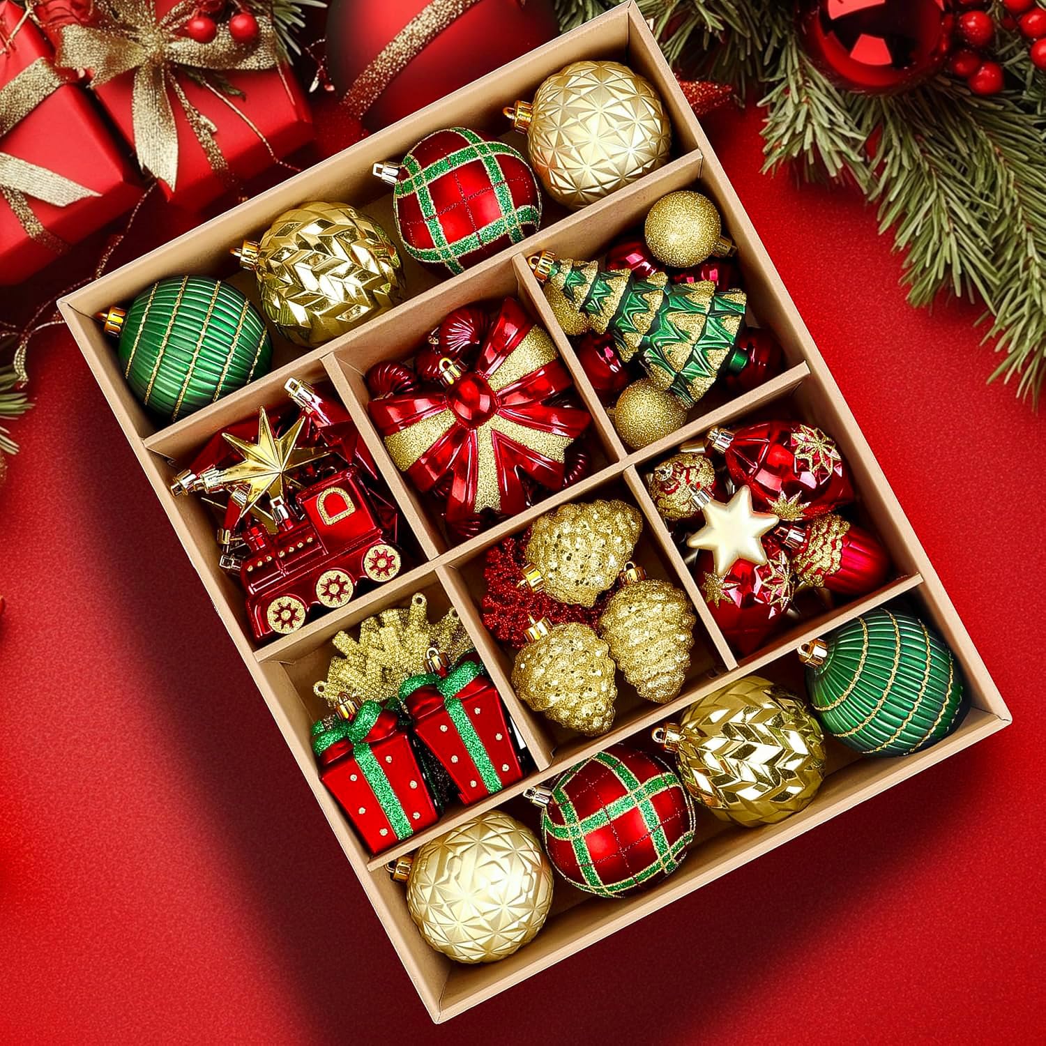 Red and green Christmas ornament set in box, surrounded by pine tree branches and gifts