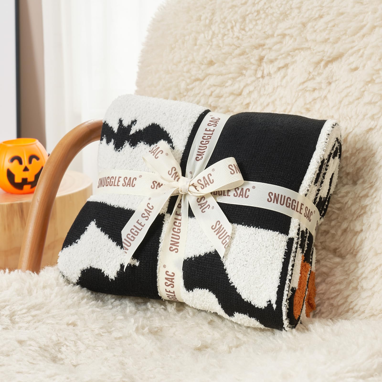 Black and white patterned Halloween blanket with 'Snuggle Sac' branding on a fluffy surface.