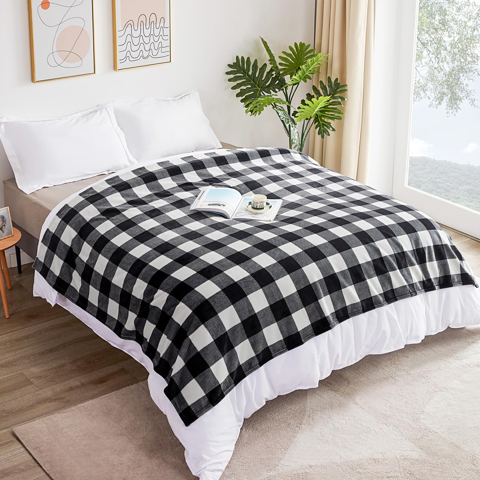 Black and white checkered blanket on a bed in a bright bedroom with a plant and framed art.