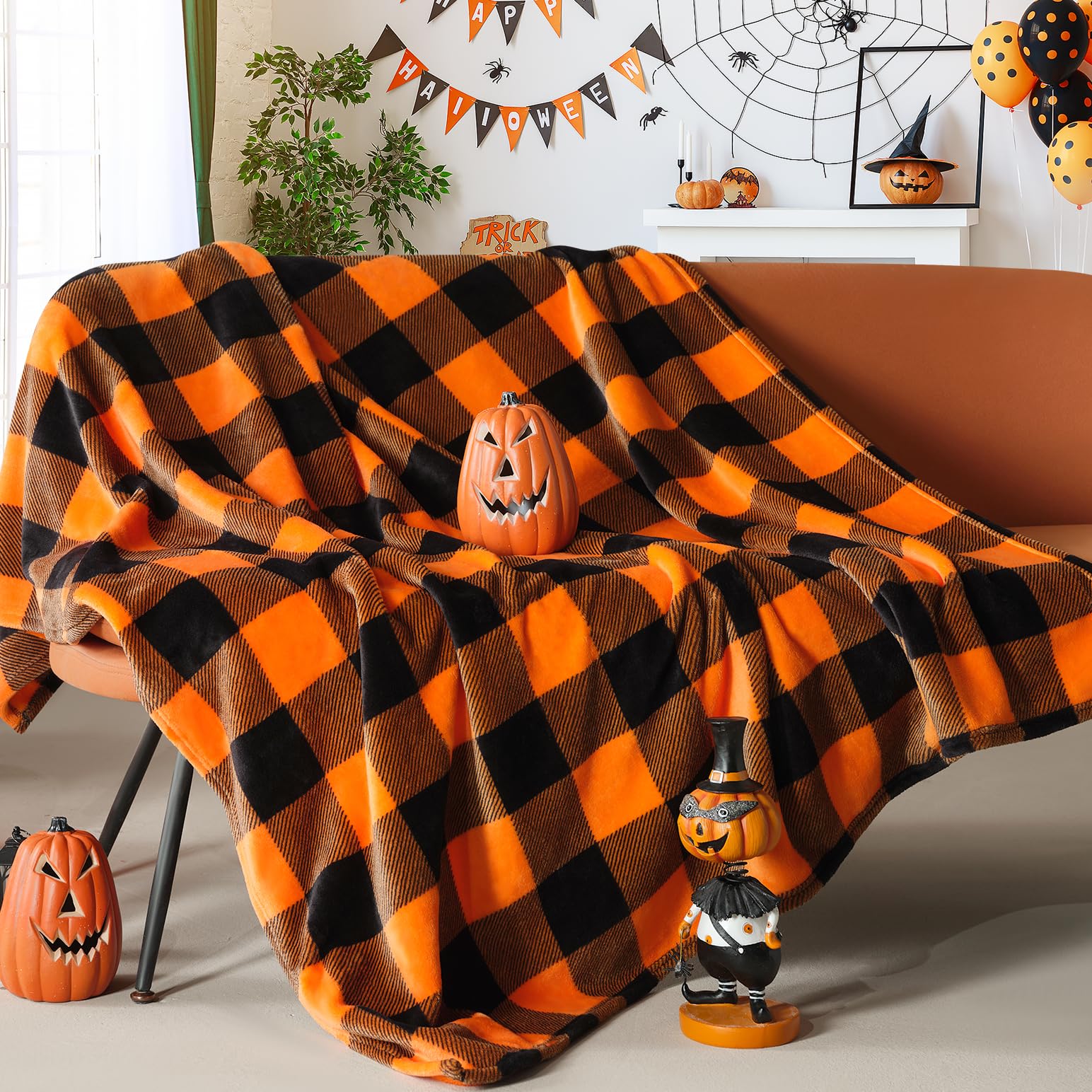Halloween-themed room with a checkered orange and black blanket draped over a couch, surrounded by pumpkins and decorations.
