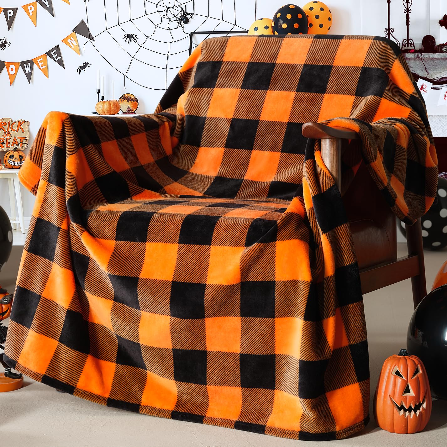 Orange and Black Buffalo Plaid Fleece Throw Blanket draped over a chair with Halloween decorations in the background.