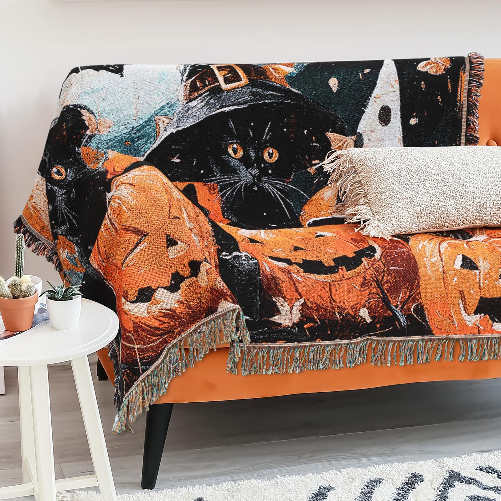 Halloween blanket with black cat and pumpkin design draped over a couch.