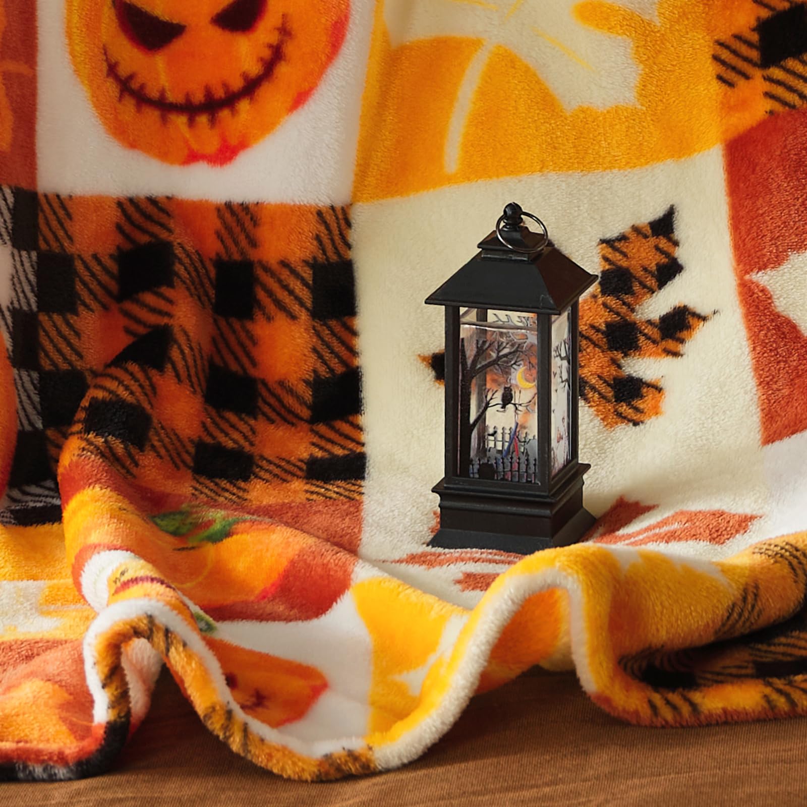 Halloween-themed blanket with pumpkins and plaid patterns, featuring a decorative lantern.