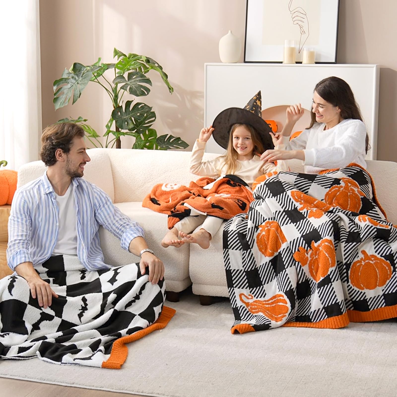 Family sitting on a couch with Halloween-themed blankets and decorations.