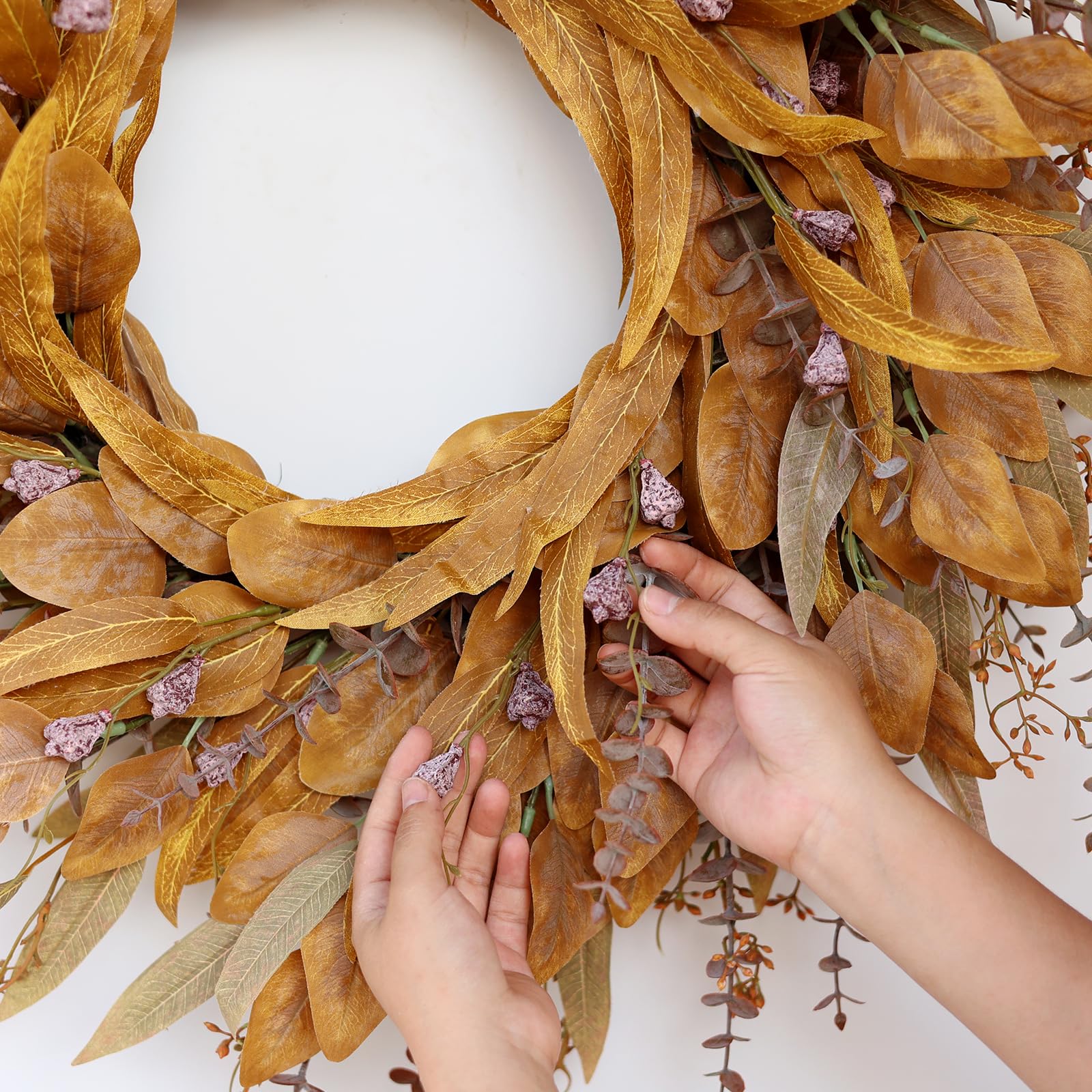 person fluffing fall wreath decoration