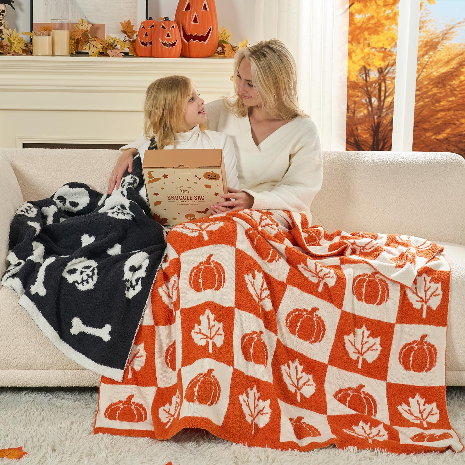 Woman and child sitting on a couch with Halloween-themed blankets and decorations.