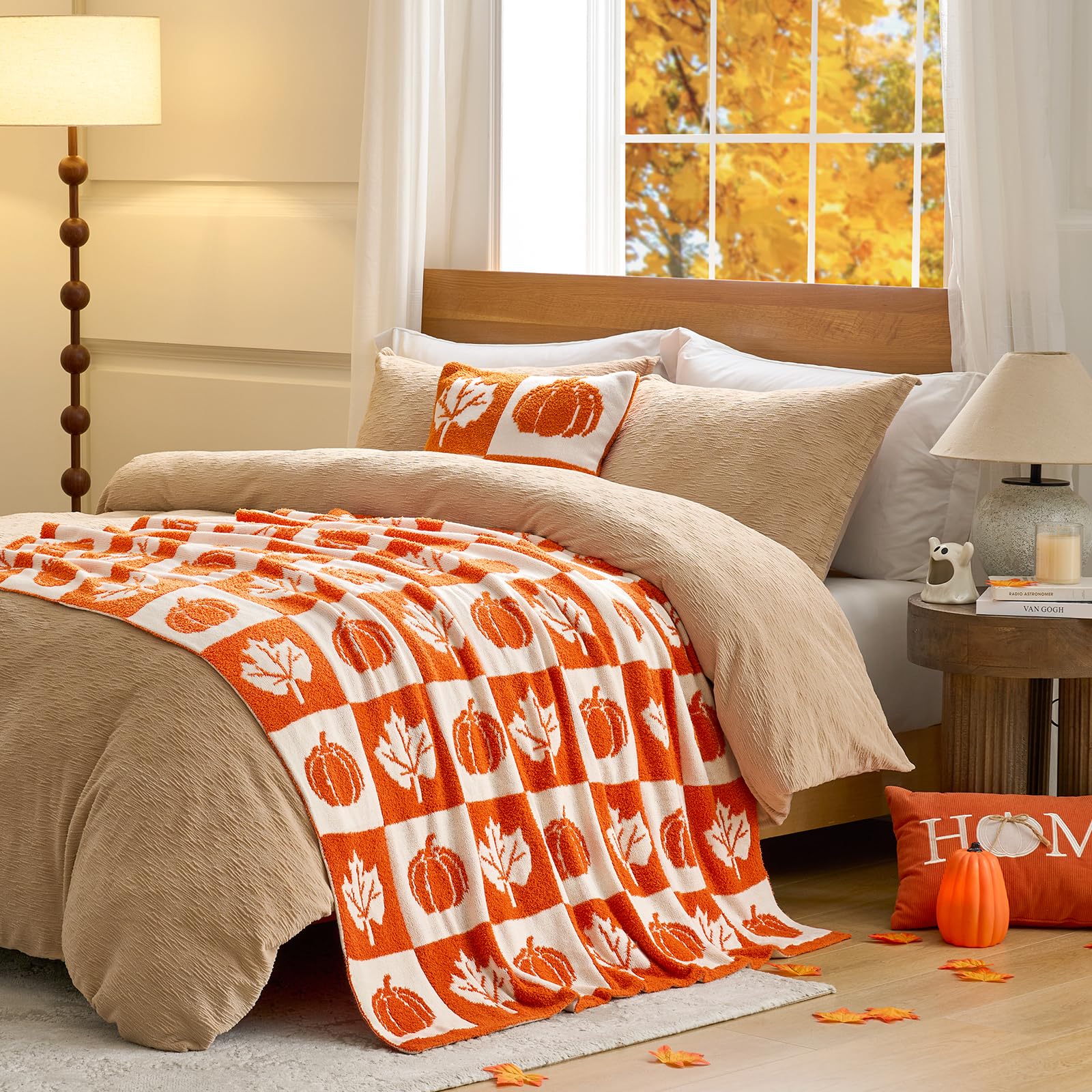 Bedroom with orange and white checkered blanket featuring pumpkins and leaves, surrounded by autumn decor.