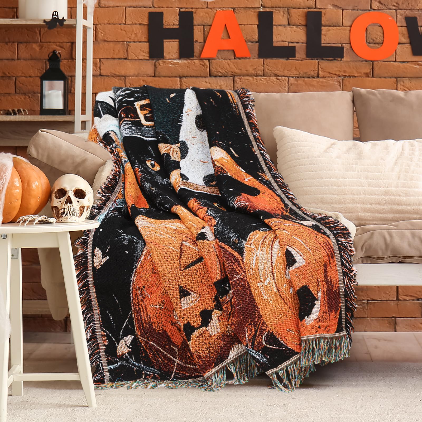 Halloween blanket with pumpkins and cats draped over a couch surrounded by Halloween decor.