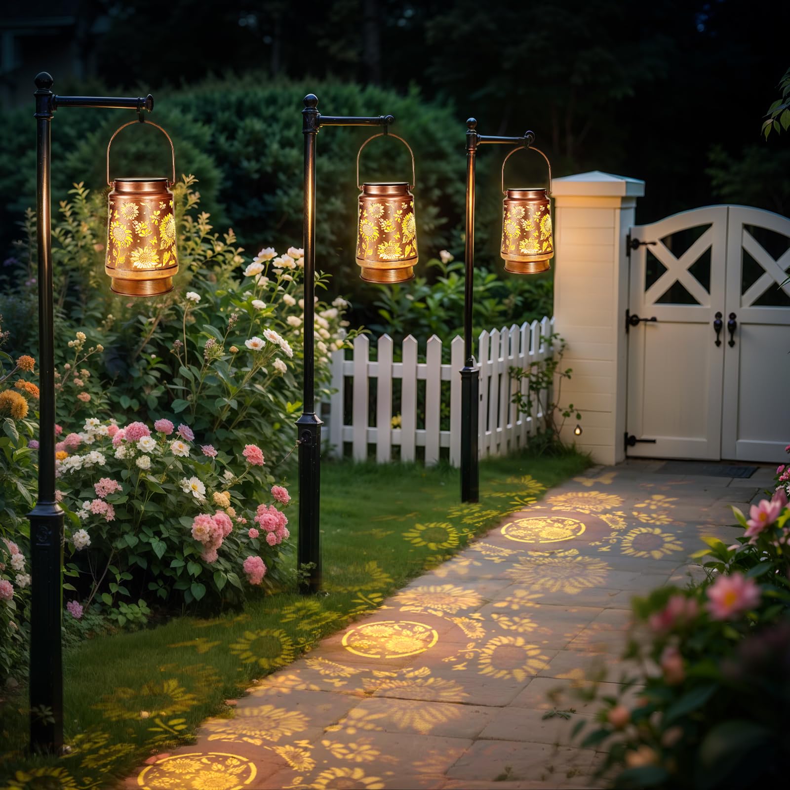 Garden pathway with decorative lanterns casting patterns on the ground, white picket fence, and white gate.