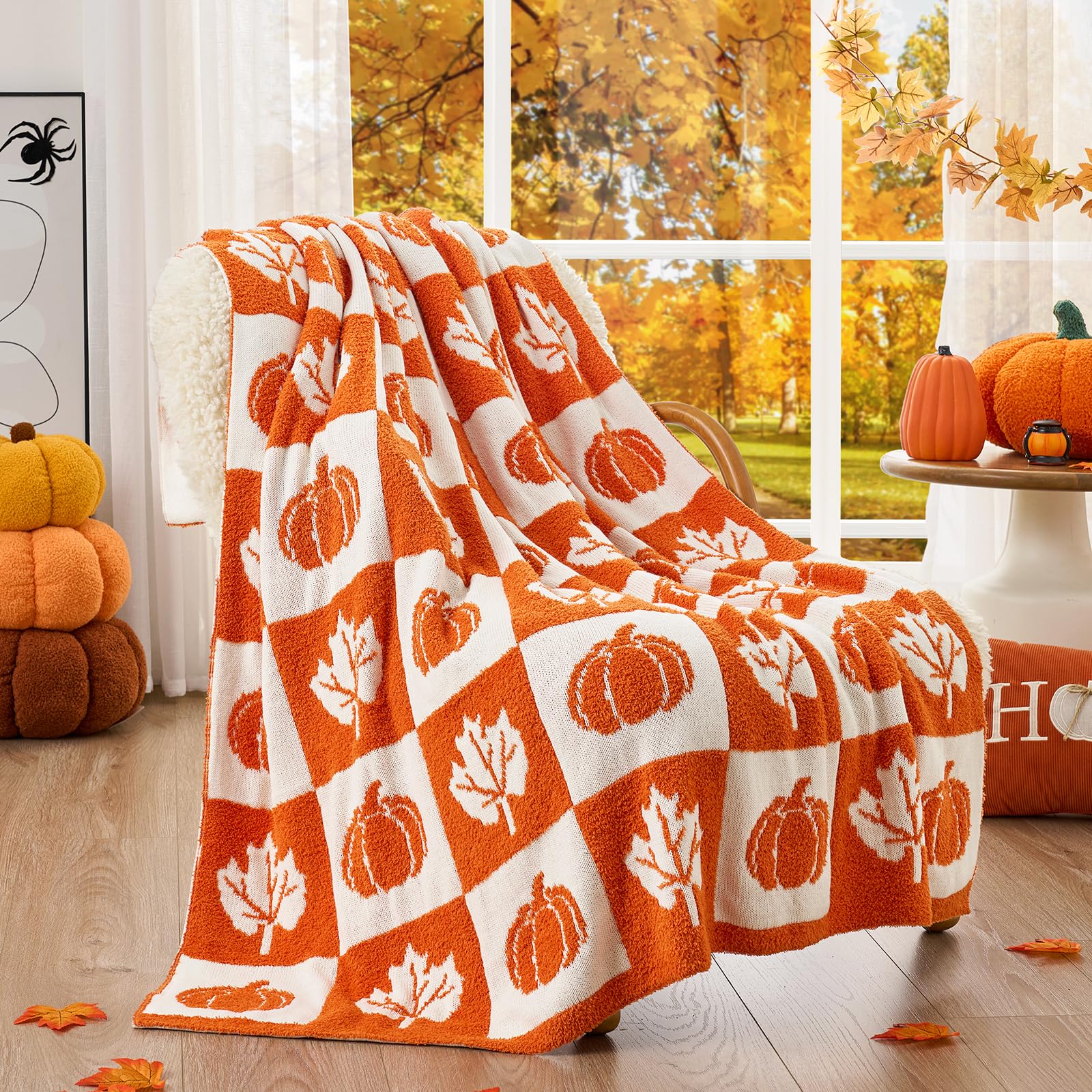 Orange and white patterned blanket with pumpkins and leaves on a chair in a room with autumn decor.