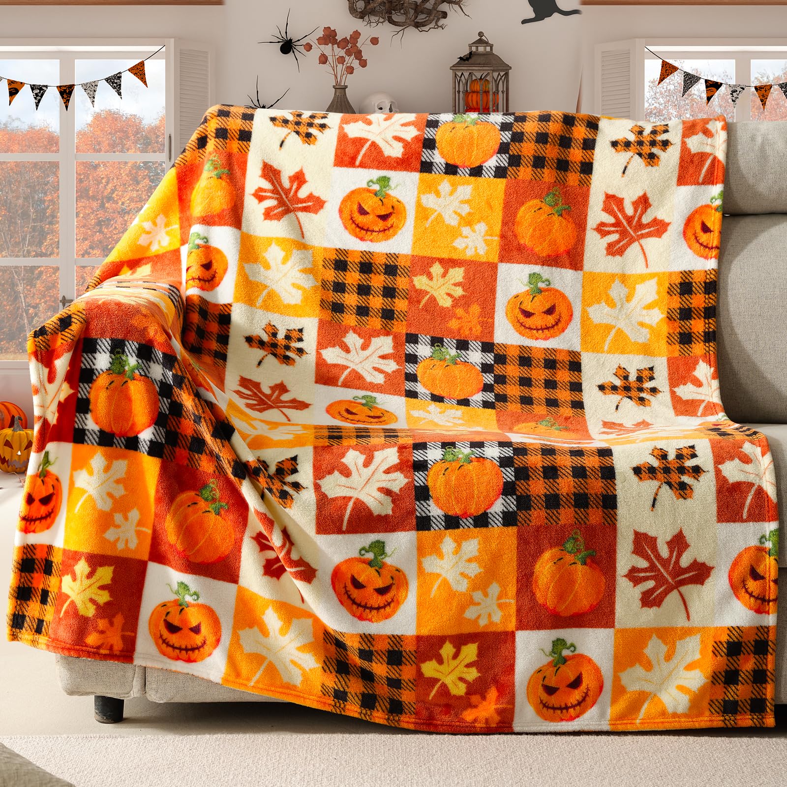 Halloween-themed blanket with pumpkins and leaves draped over a couch.